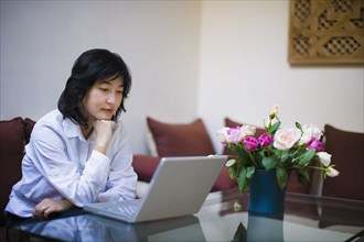 Asian woman using laptop in livingroom