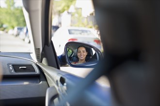 Image of Hispanic woman in car's side mirror