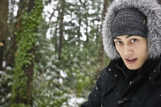Mixed race man outdoors in hooded coat