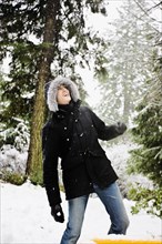 Mixed race man in hooded coat outdoors in snowfall