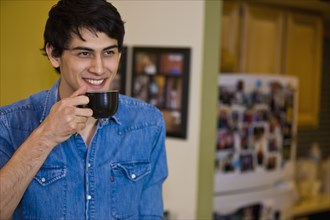 Mixed race man drinking coffee in kitchen
