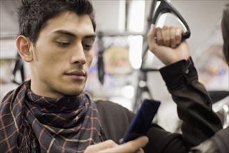 Close up of mixed race man text messaging with cell phone on subway