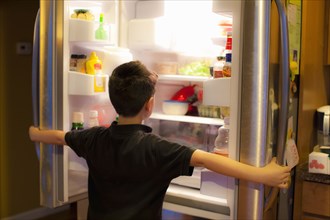 Asian boy searching through refrigerator