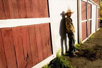Caucasian farmer leaning on barn wall