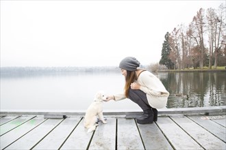 Japanese woman petting dog near lake