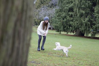 Japanese woman playing with dog in park