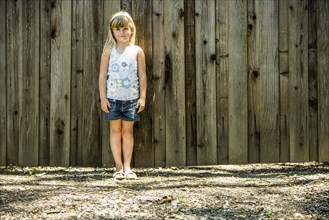 Caucasian girl standing at wooden fence