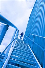 Blue collar worker at top of industrial staircase