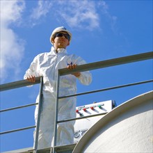 Caucasian man wearing coveralls leaning on railing