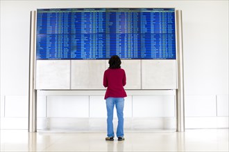 Japanese woman reading departure schedules at airport
