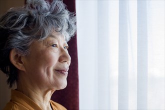 Smiling Japanese woman standing at window