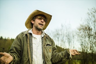 Caucasian farmer wearing cowboy hat talking and gesturing outdoors