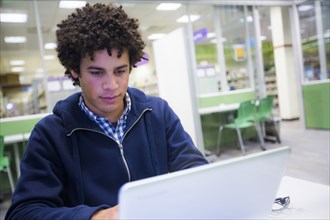 Mixed Race student using laptop in library