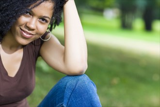Smiling Mixed Race woman sitting in park