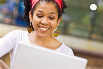 Laughing Mixed Race woman using laptop