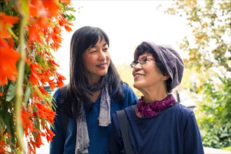 Older Japanese mother and daughter near autumn leaves