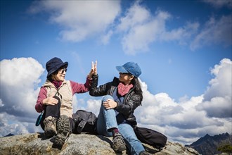 Older Japanese mother and daughter high-fiving on rock