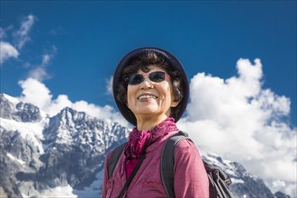 Older Japanese woman smiling near mountain