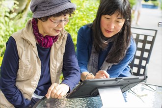 Older Japanese mother and daughter using digital tablet