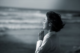 Japanese woman meditating at beach