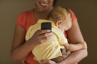 Mother text messaging while holding sleeping child