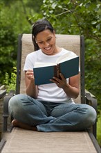 African American woman reading book in back yard