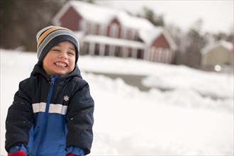 Grinning mixed race boy standing in snow