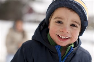 Mixed race smiling boy outdoors in coat and cap
