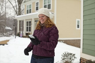 Caucasian woman using cell phone in snow