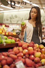 Mixed race woman buying produce in supermarket
