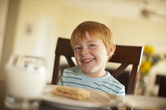 Caucasian boy giggling at dinner table