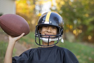 Mixed race boy playing football outdoors