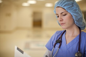 Caucasian nurse reading medical chart in hospital