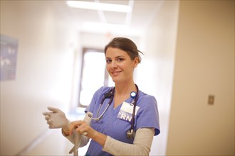Caucasian nurse pulling on gloves in hospital