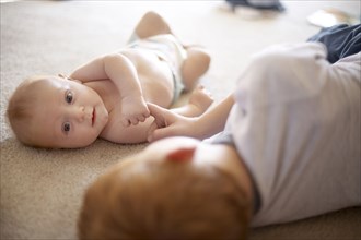 Caucasian boy playing with baby brother on carpet