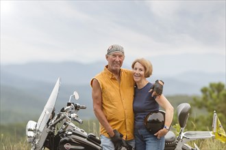Older Caucasian couple smiling on motorcycle