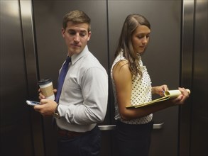 Business people ignoring each other in elevator