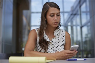 Mixed race businesswoman using cell phone at desk