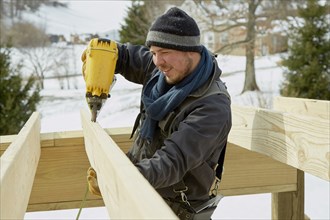Caucasian carpenter using power drill in winter
