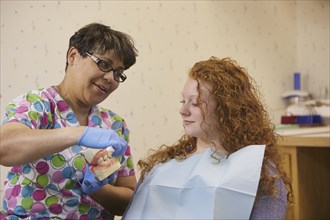 Pediatric dentist showing teeth model to teenage patient