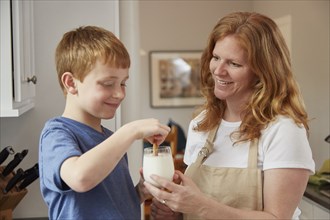 Caucasian mother and son dunking cookies in milk