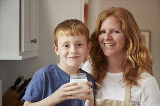 Caucasian mother and son drinking milk in kitchen