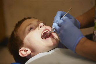 Pediatric dentist examining teeth of patient