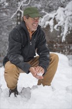 Mixed race man making snowballs in snow