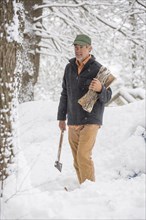Mixed race man carrying firewood in snowy forest