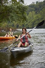 Women paddling kayaks in remote river