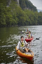 Friends paddling kayaks in remote river