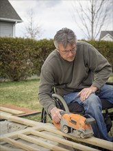 Caucasian paraplegic man wood working in backyard