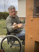 Caucasian paraplegic man painting deck in backyard