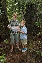 Caucasian boys reading map in forest